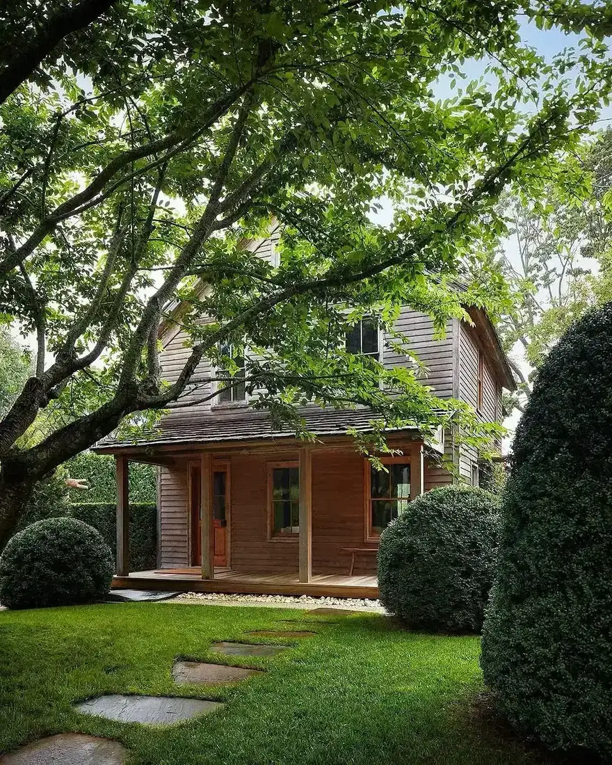 Weathered clapboard farmhouse under a large oak tree on a wide lawn