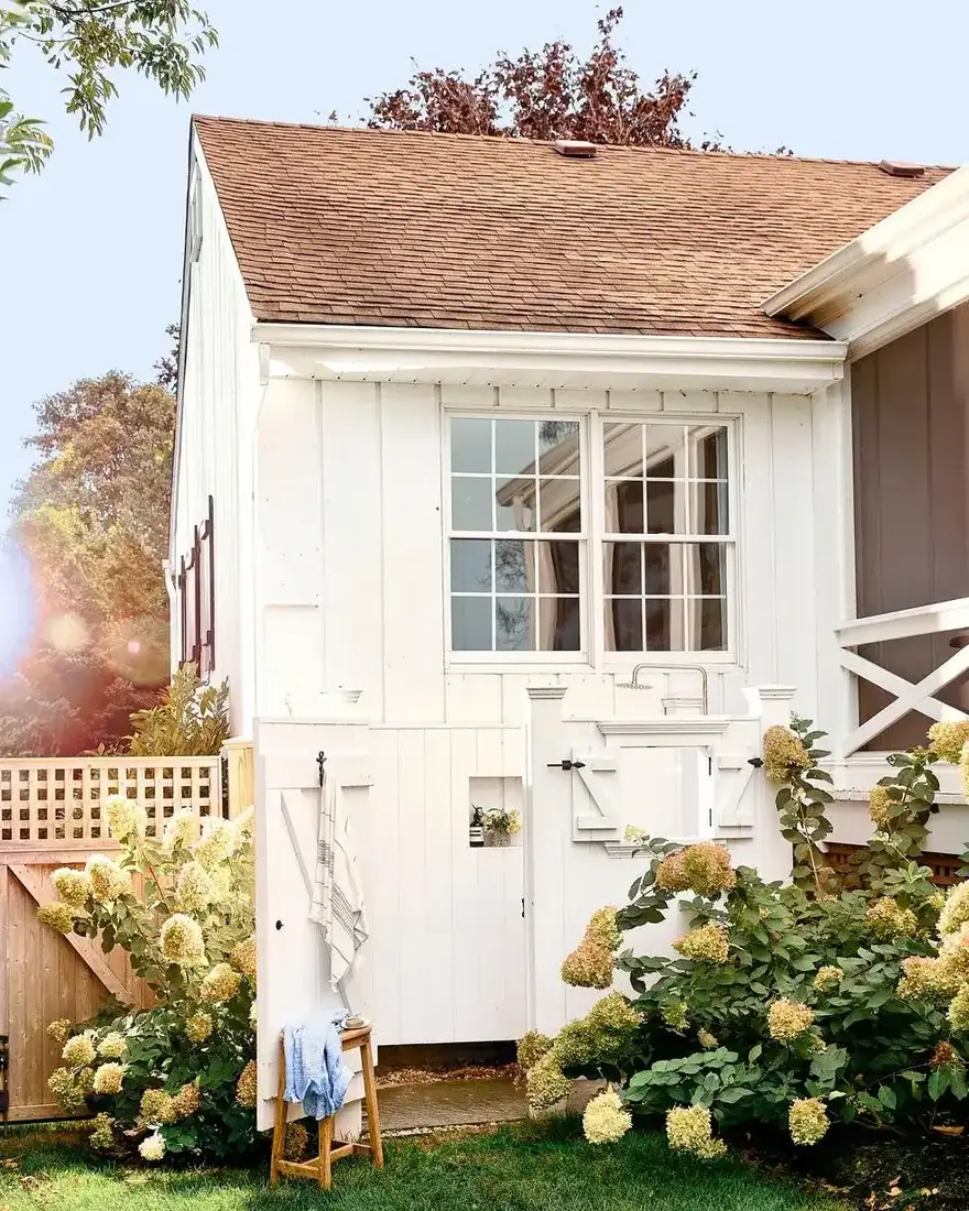 White board and batten cottage with hydrangeas and a light blue Dutch door