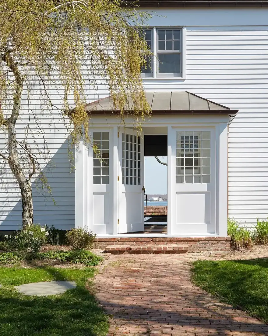 White clapboard house with modern glass entry porch and black framing