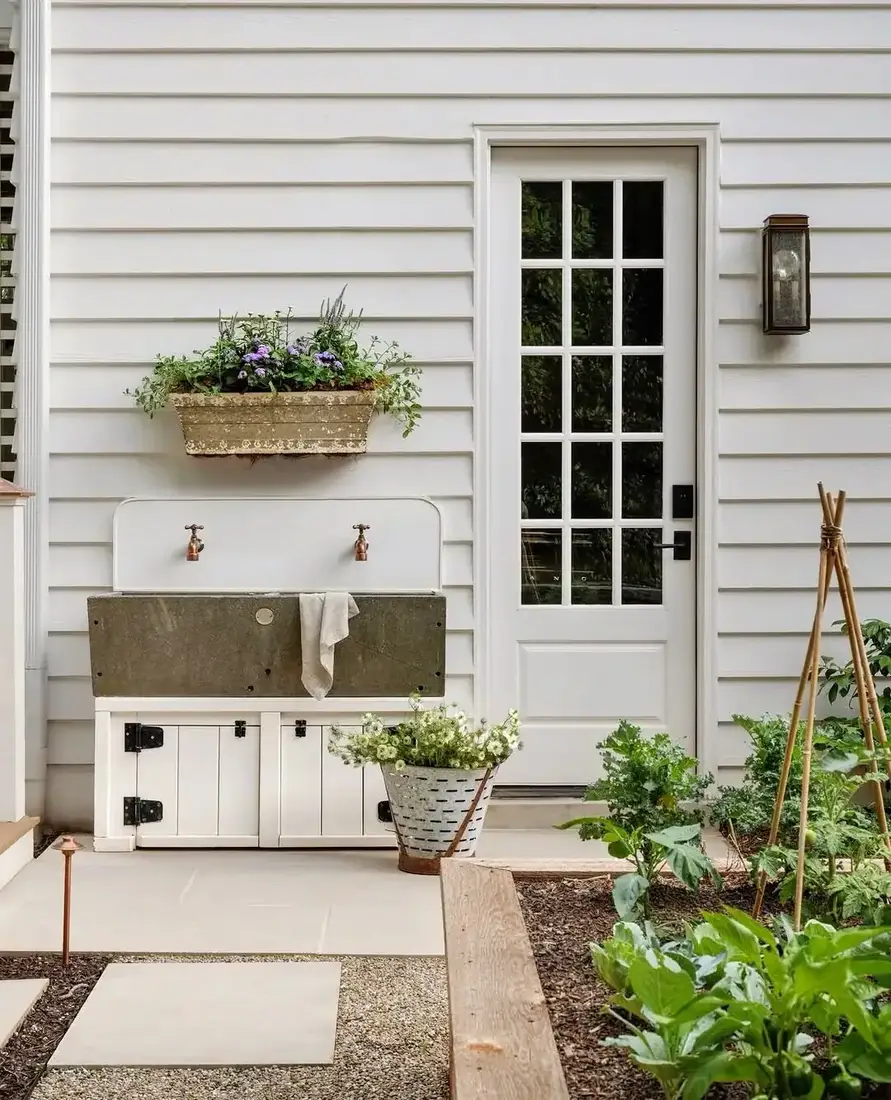 White clapboard wall with outdoor sink and flowering window box