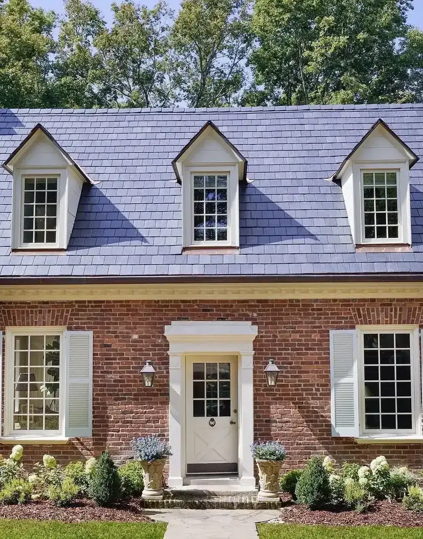 Red brick colonial house with a slate roof, three dormer windows and a white panelled front door