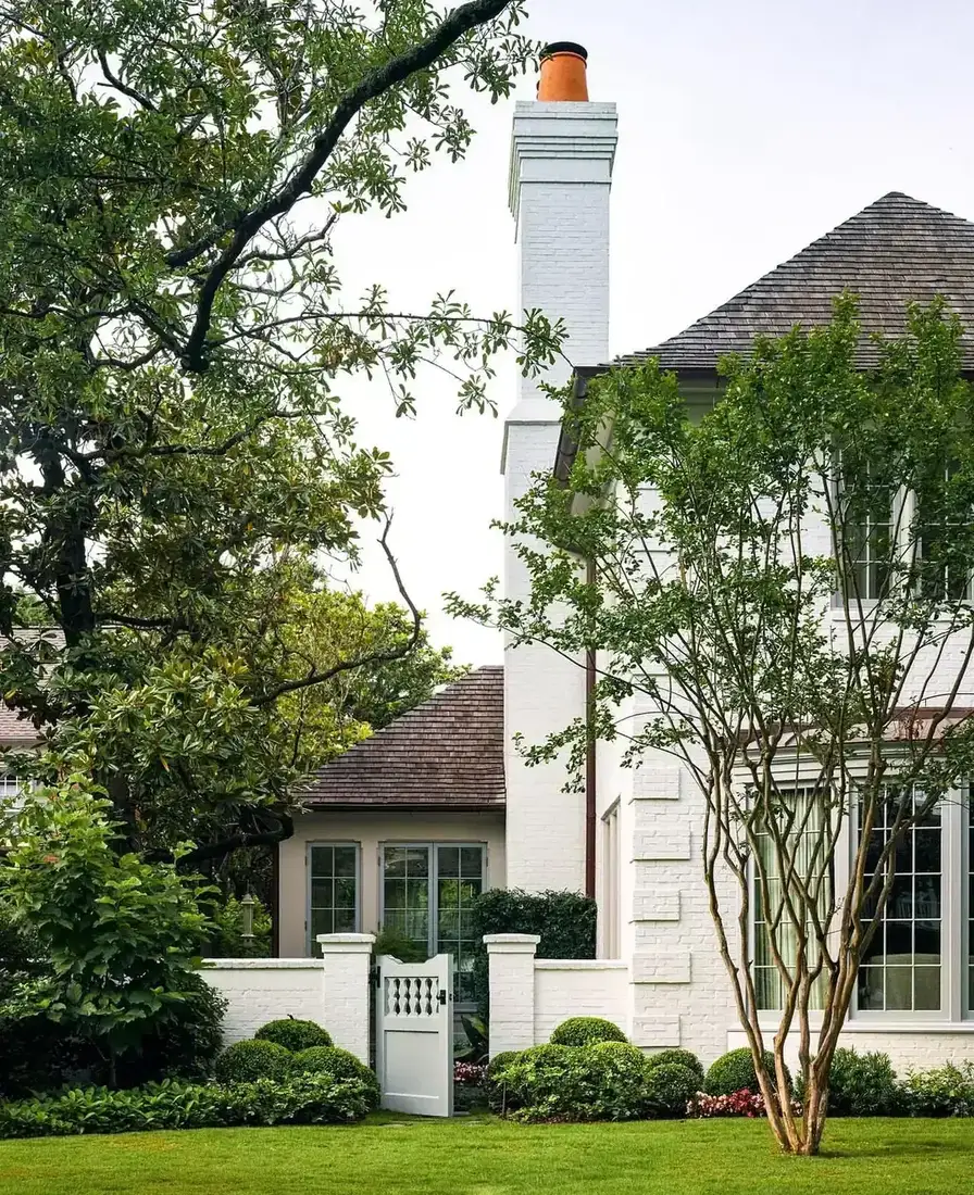 White brick Tudor cottage with a neat front garden and clipped hedging