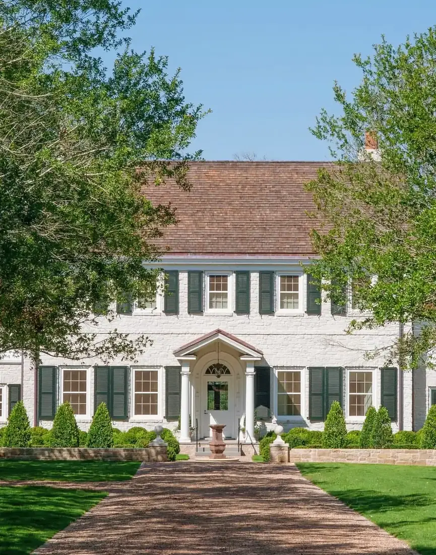 Whitewashed brick colonial house with black shutters and symmetrical front elevation