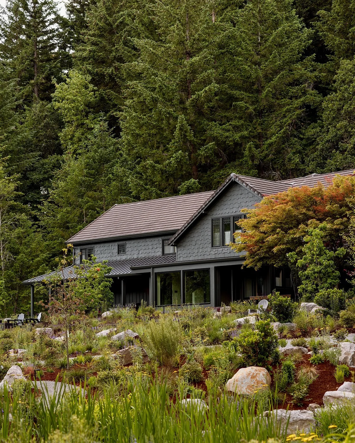 Dark cabin in a forest clearing with a wildflower meadow