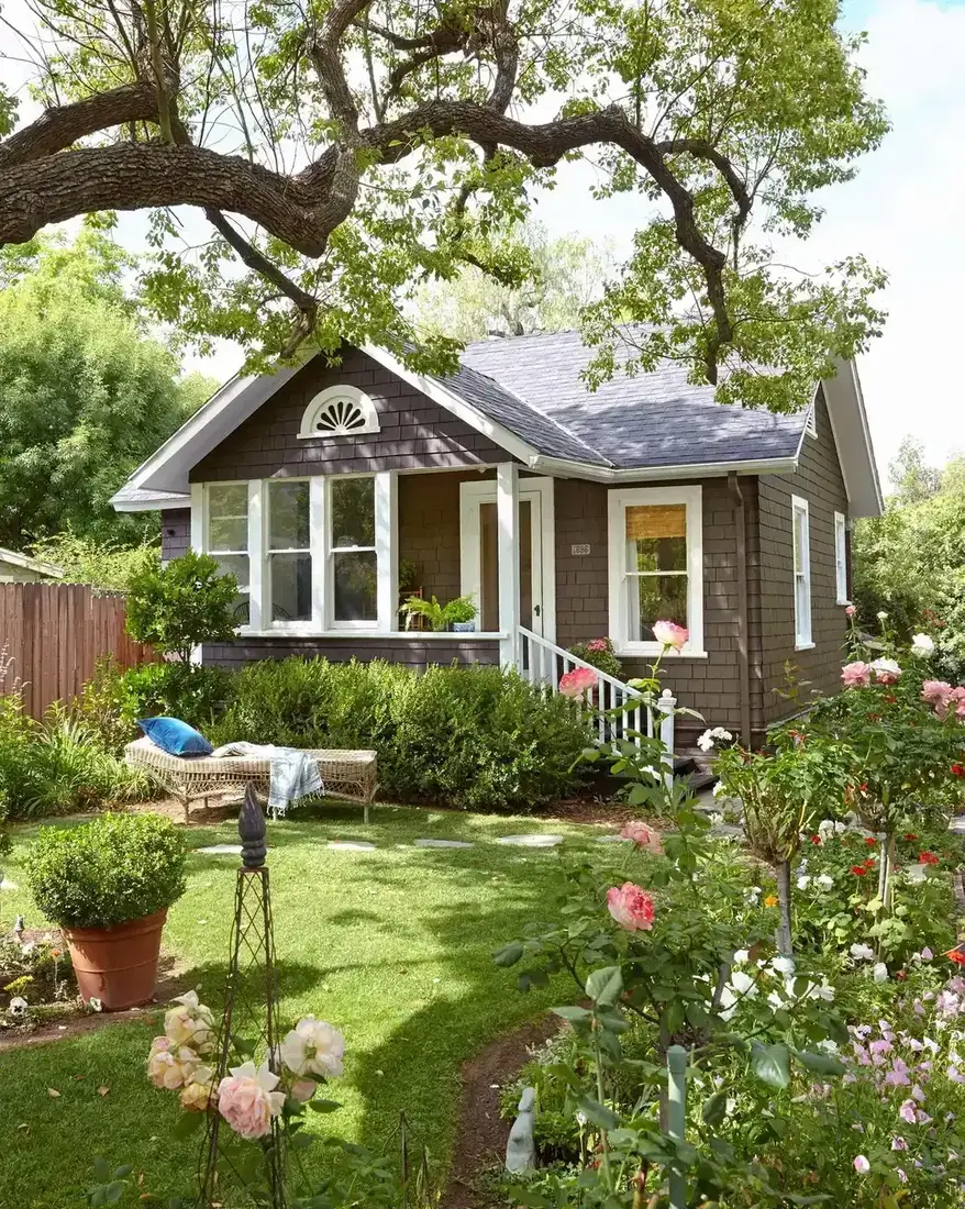 Brown shingle bungalow with mature rose garden along the front path