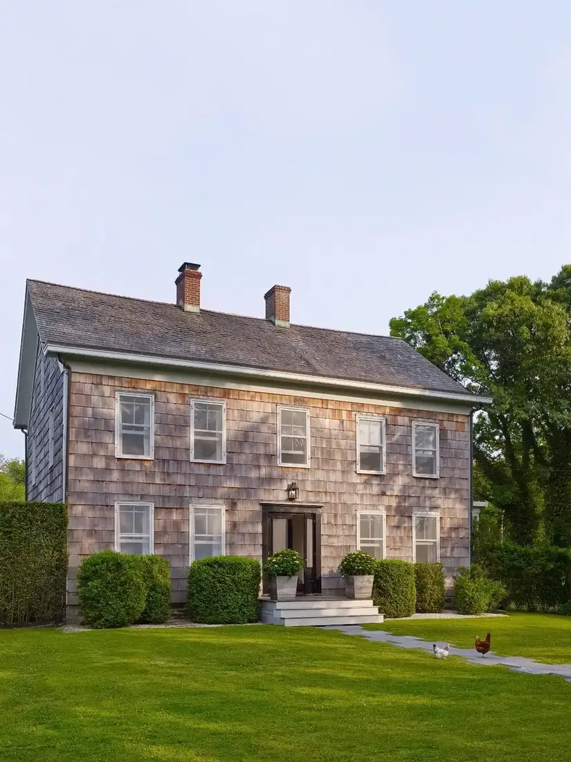 Cedar shingle saltbox colonial house with long pitched roof and white trim