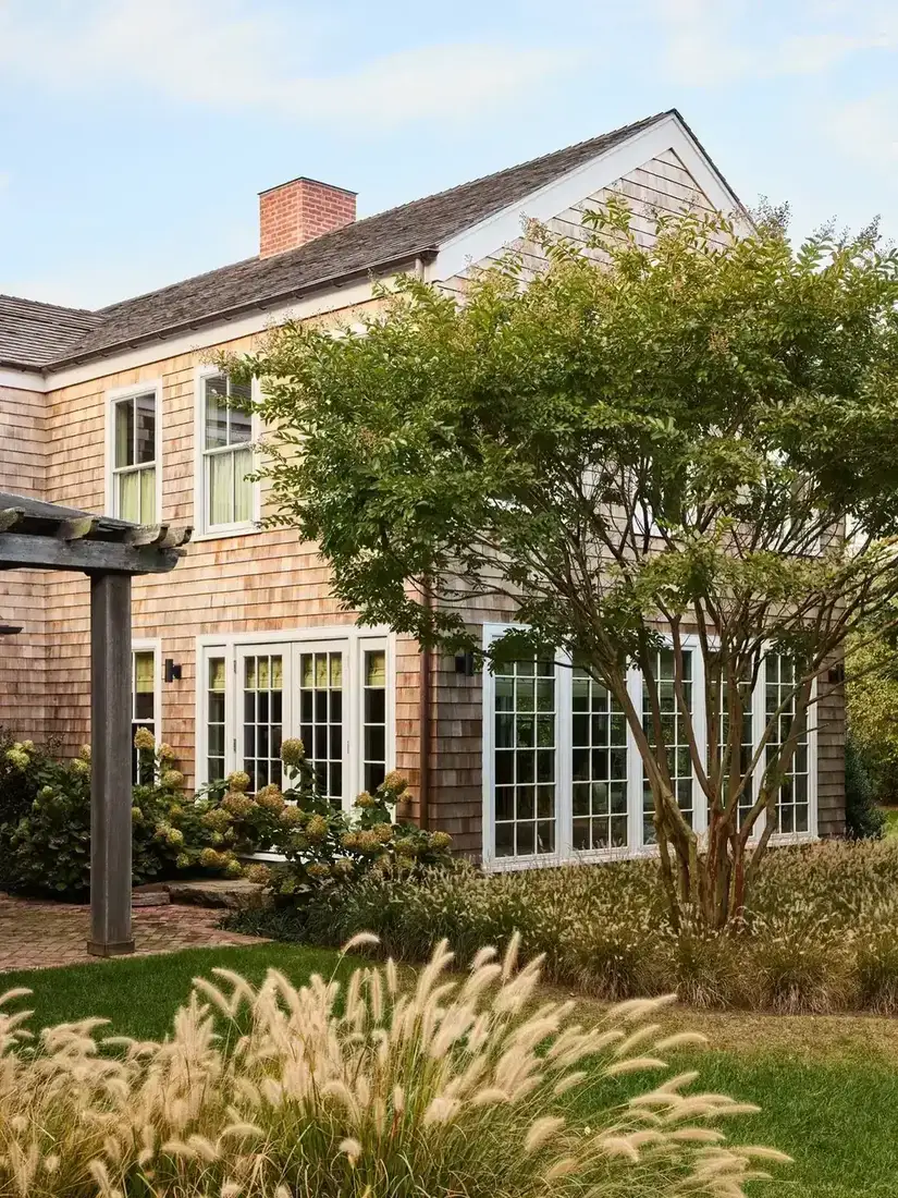 Cedar shingle house with white window trim and planted front garden