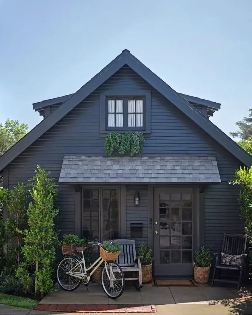 Charcoal shingle cottage with canvas awning and bicycle by the front path