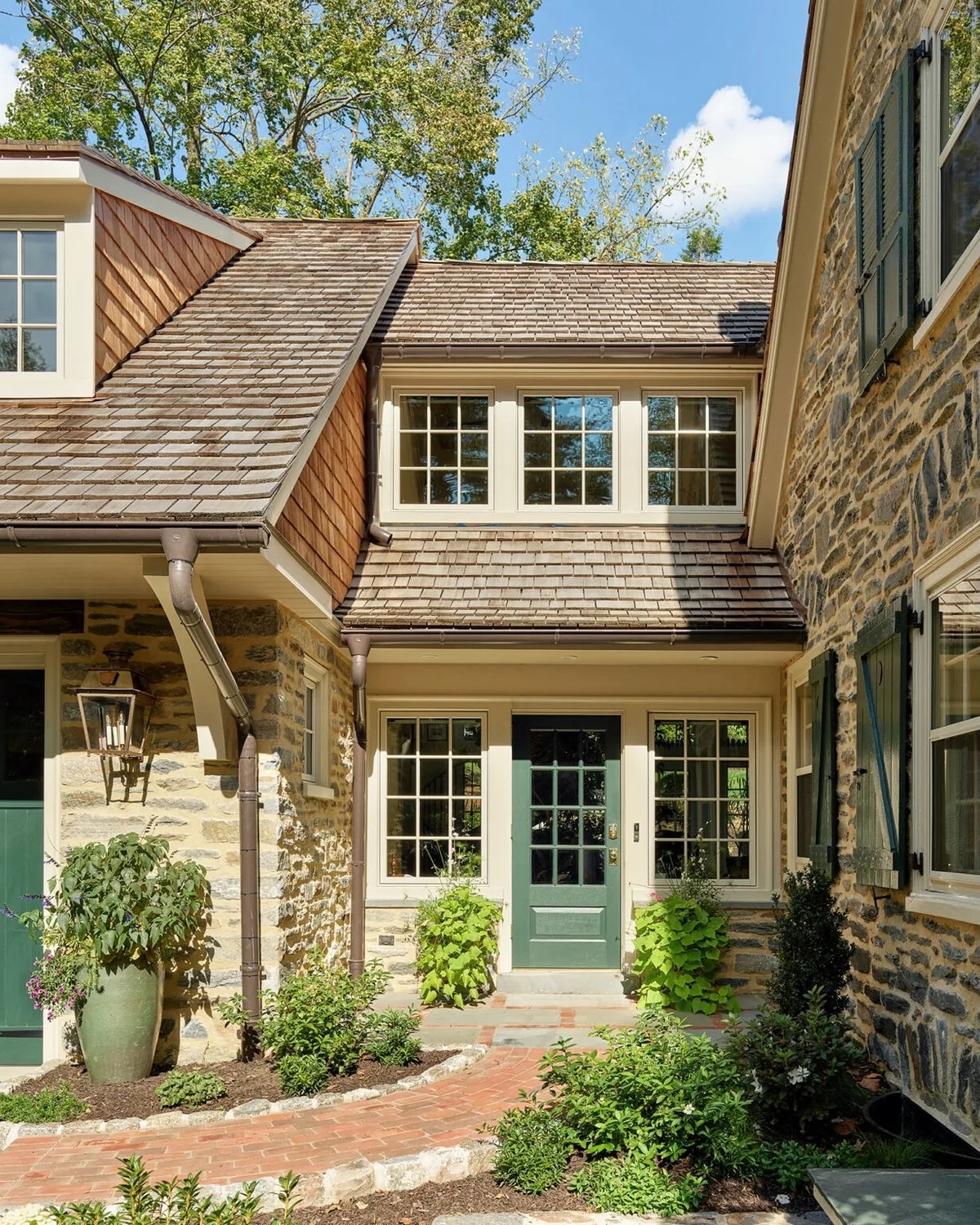 Stone cottage with cedar shingle siding and a green front door