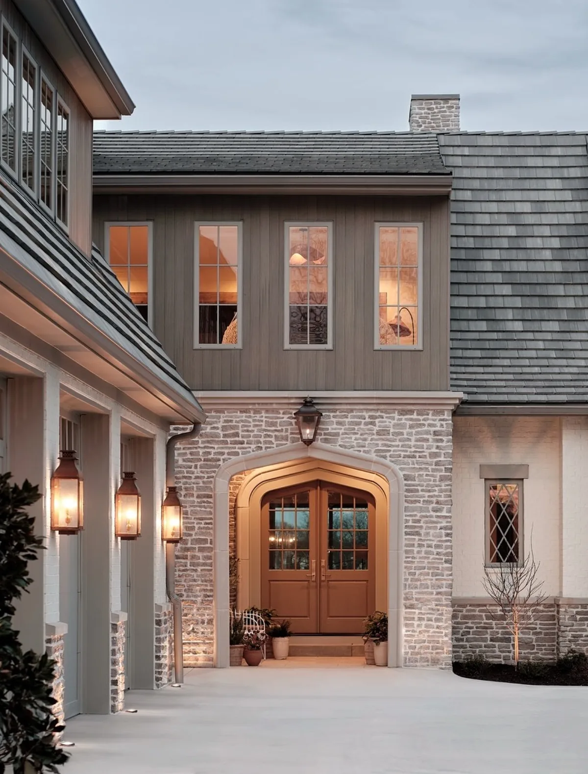 Stone and shingle house with an arched wood front door