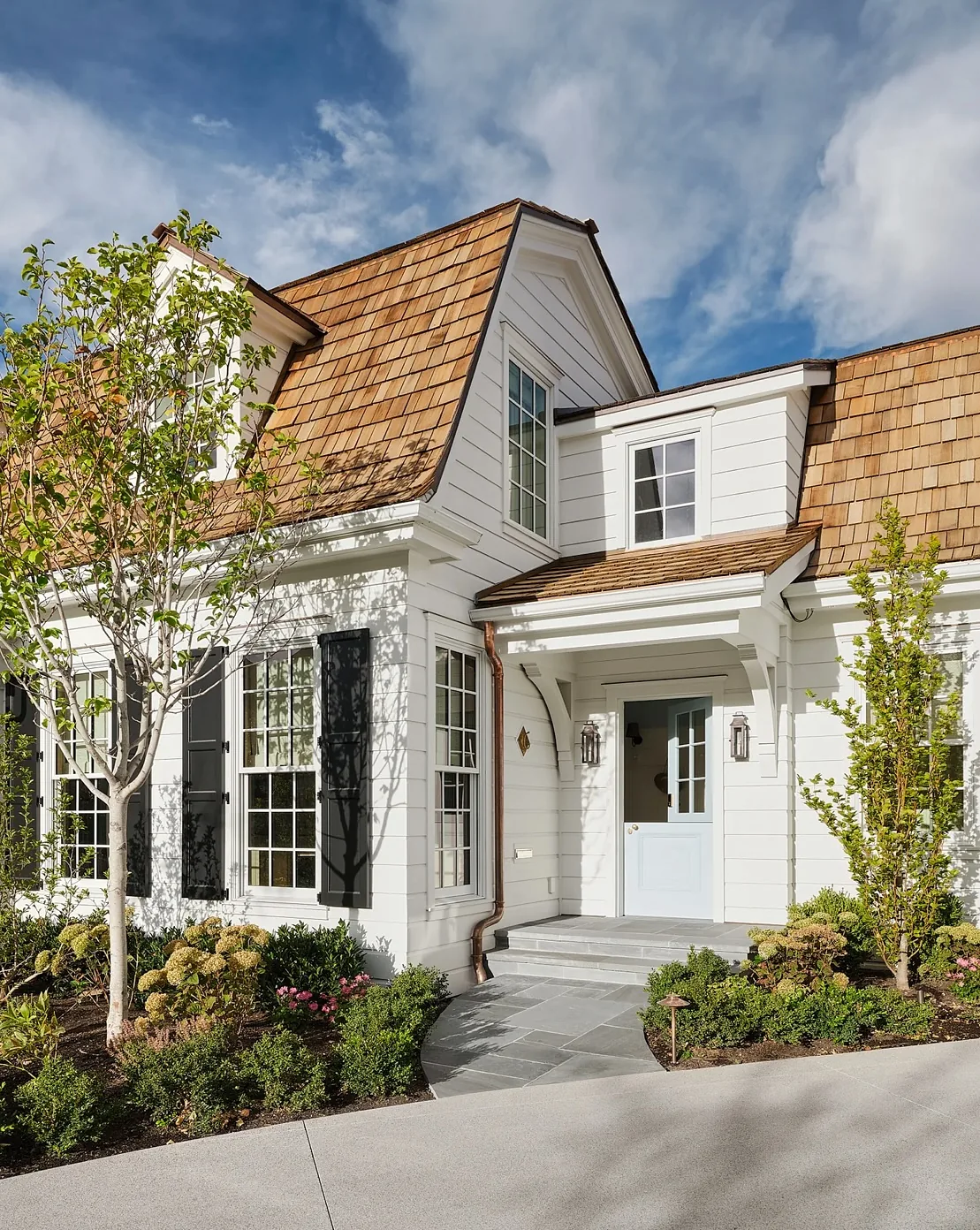 White cottage with a cedar shake gable and dormer