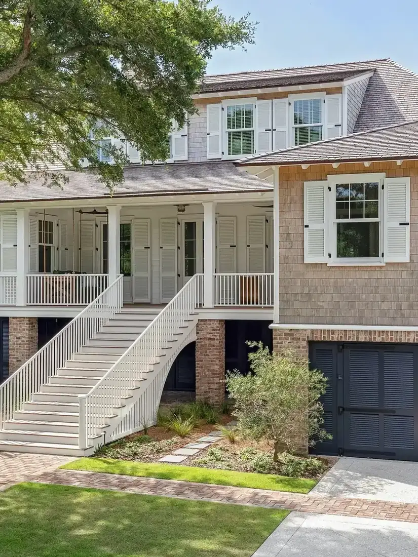 Grey shingle house with white double staircase and symmetrical entry