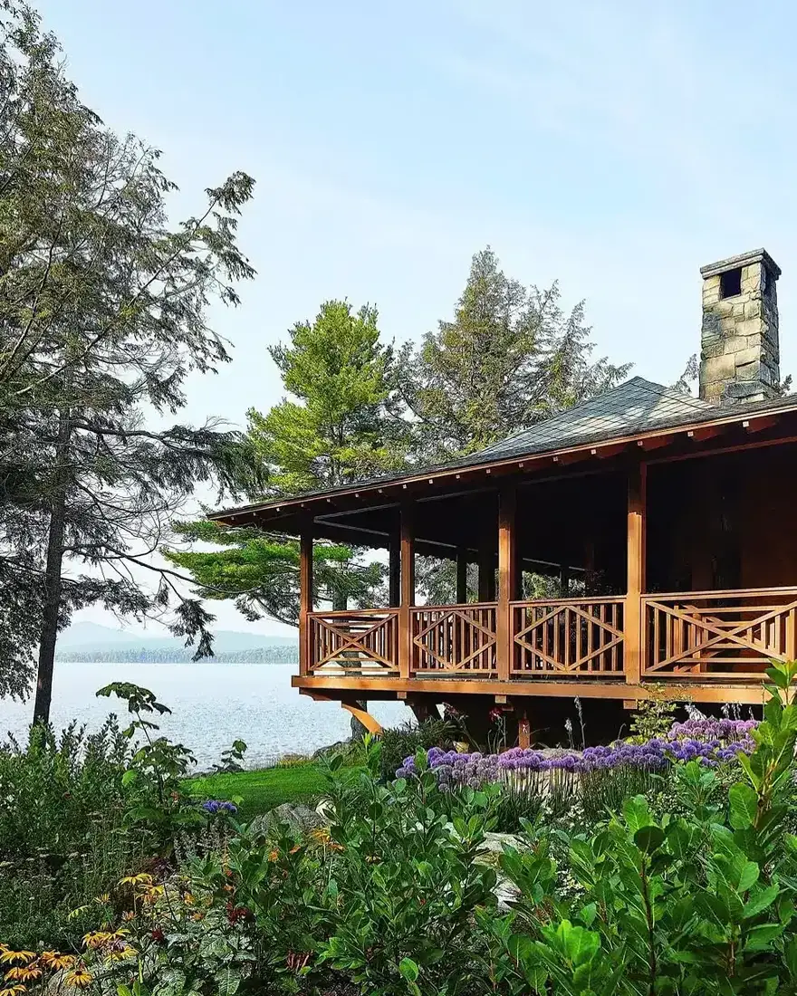 Lakeside shingle cottage with twig railing porch overlooking water