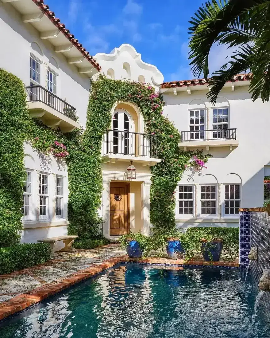 Spanish colonial villa with bougainvillea and pool surrounded by palm trees