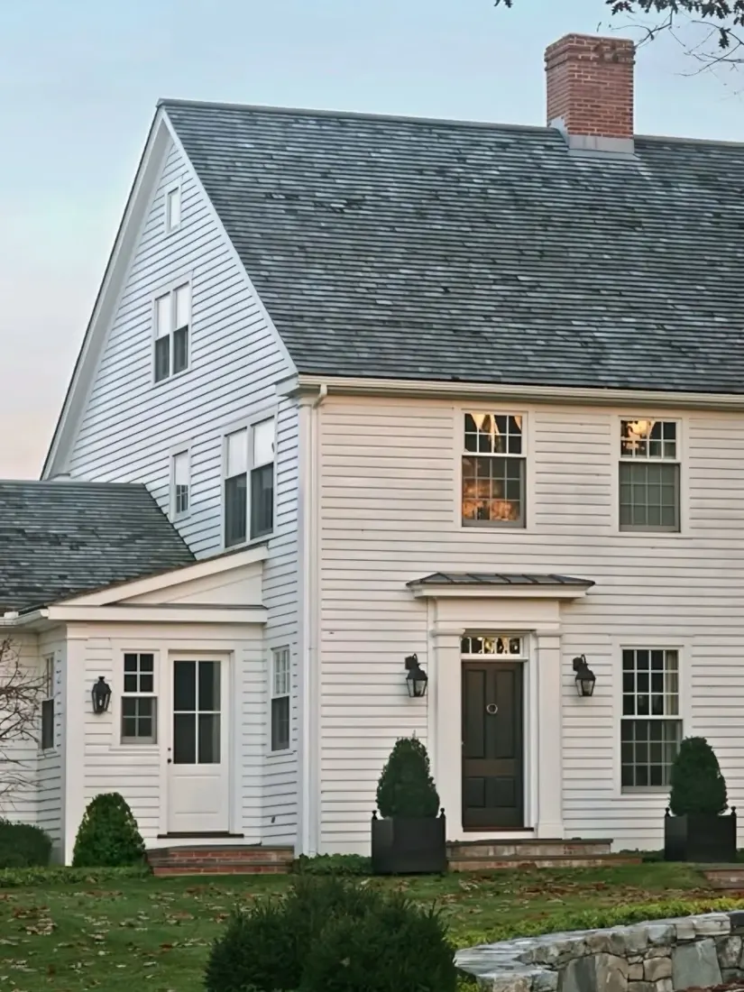White clapboard colonial with black front door and triangular pediment