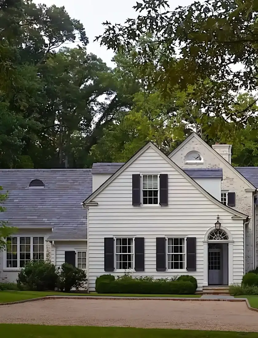 White colonial house with black shutters and a dark slate roof