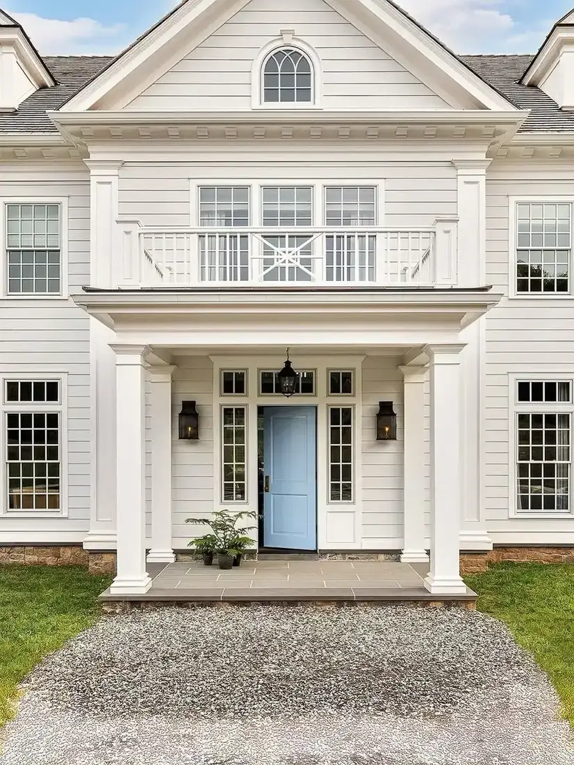 White colonial house with blue front door and second floor balcony