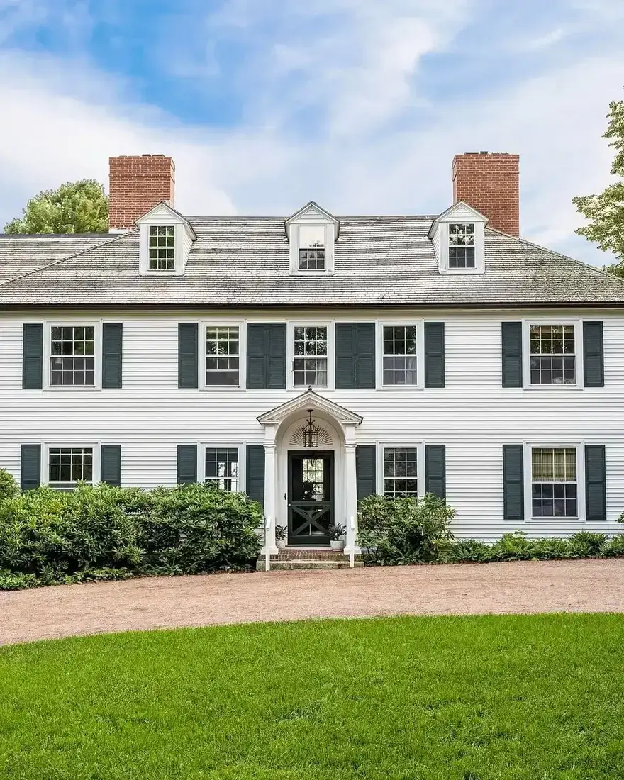 White colonial house with black shutters and classic symmetrical facade