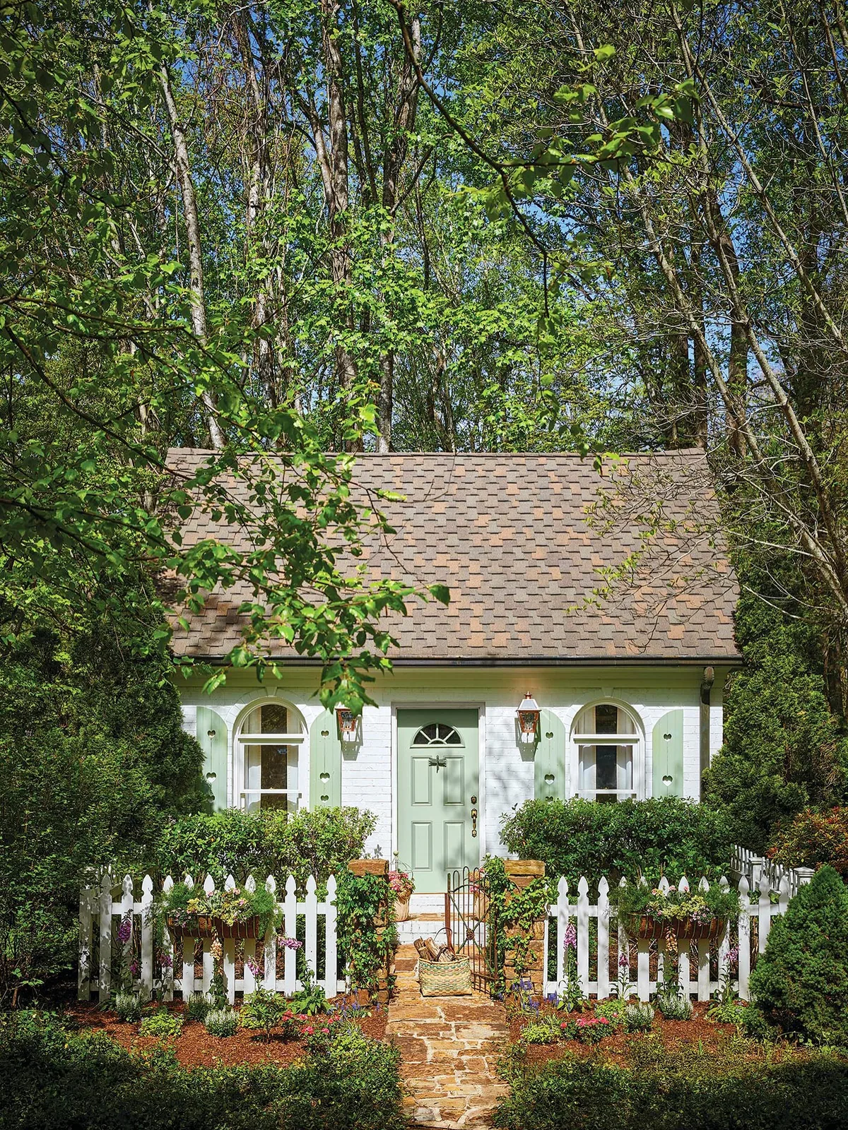 Green shuttered cottage with a white picket fence
