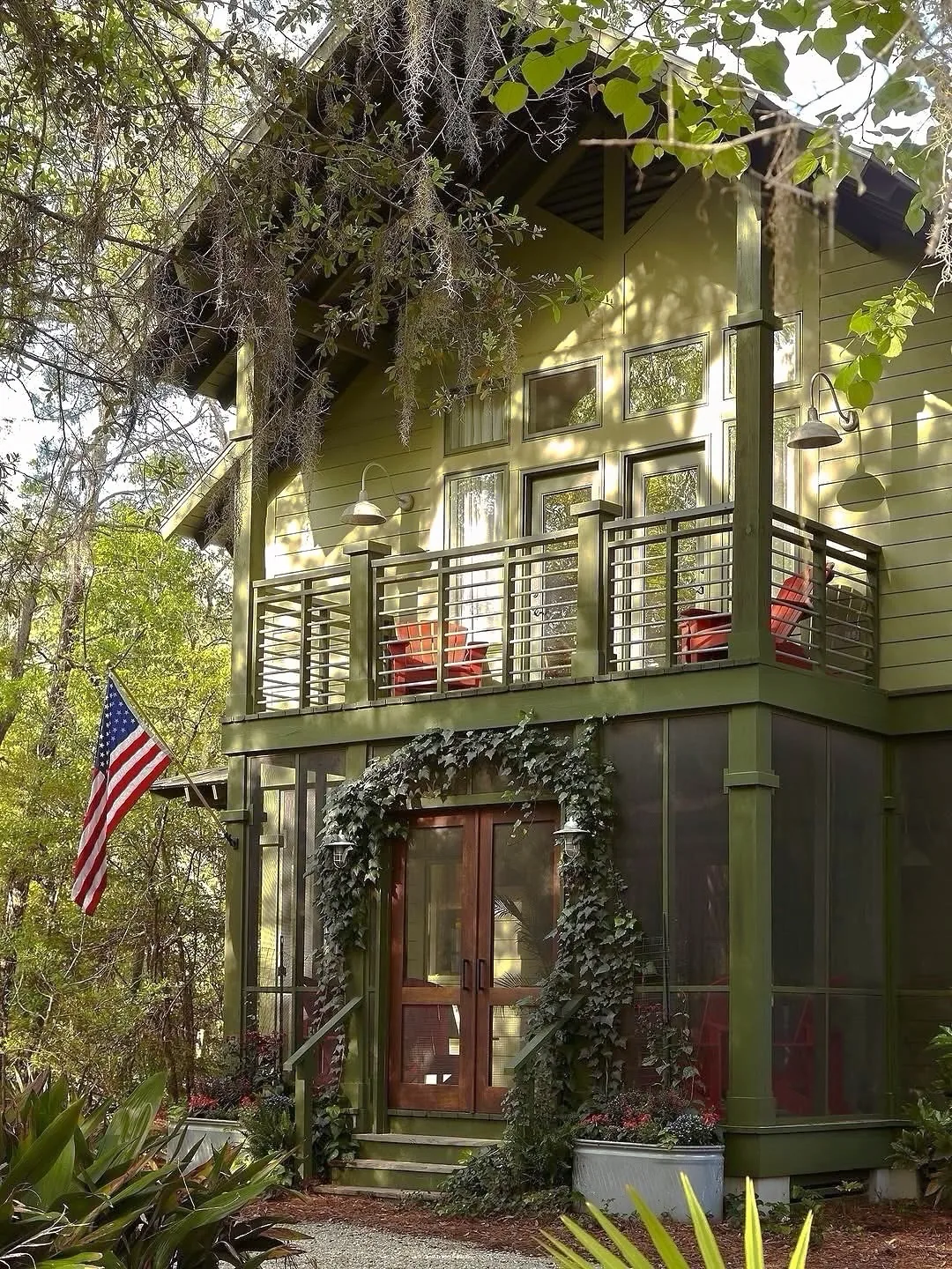 Olive green cottage with a balcony and American flag