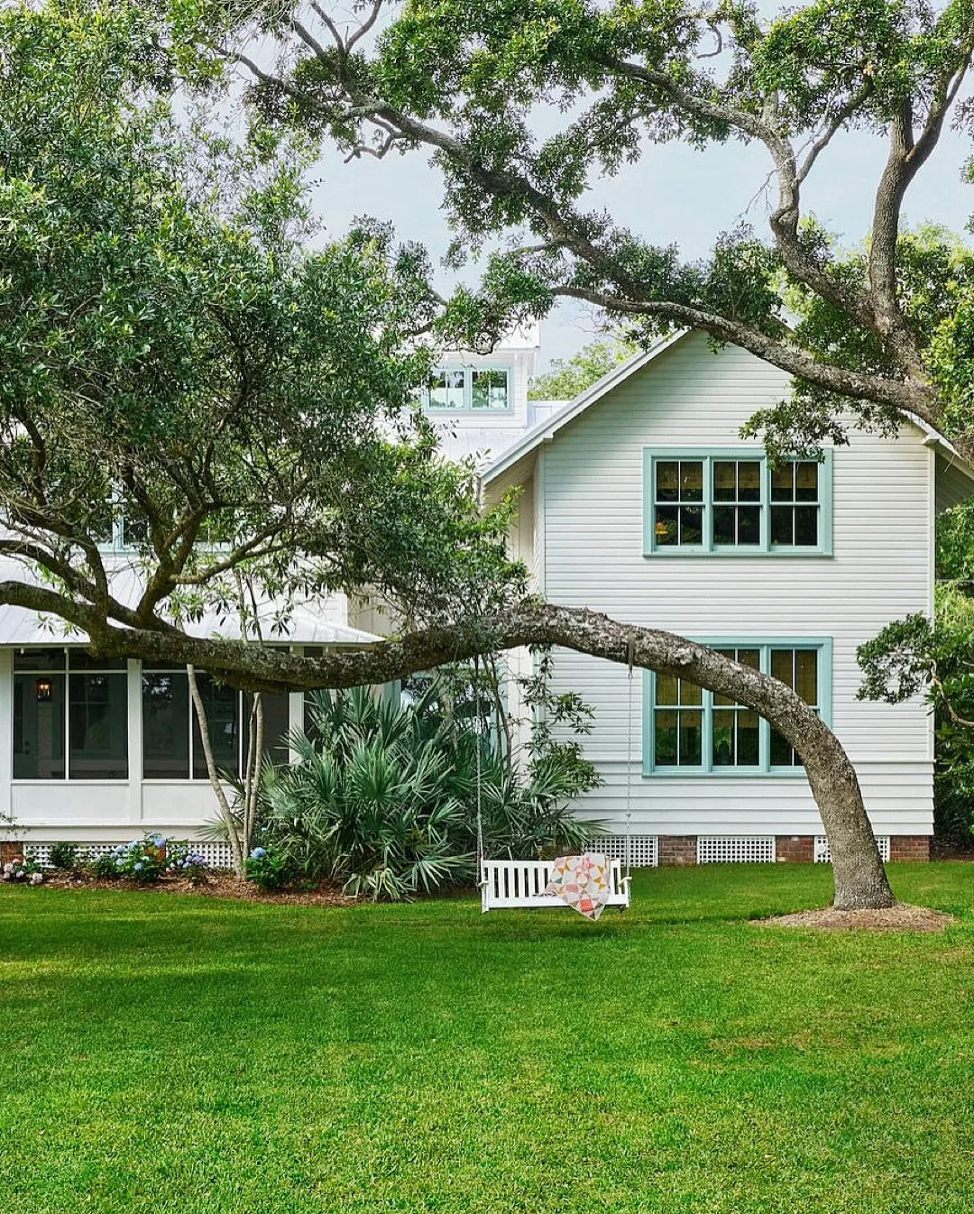 Pale blue cottage under a live oak with a porch swing