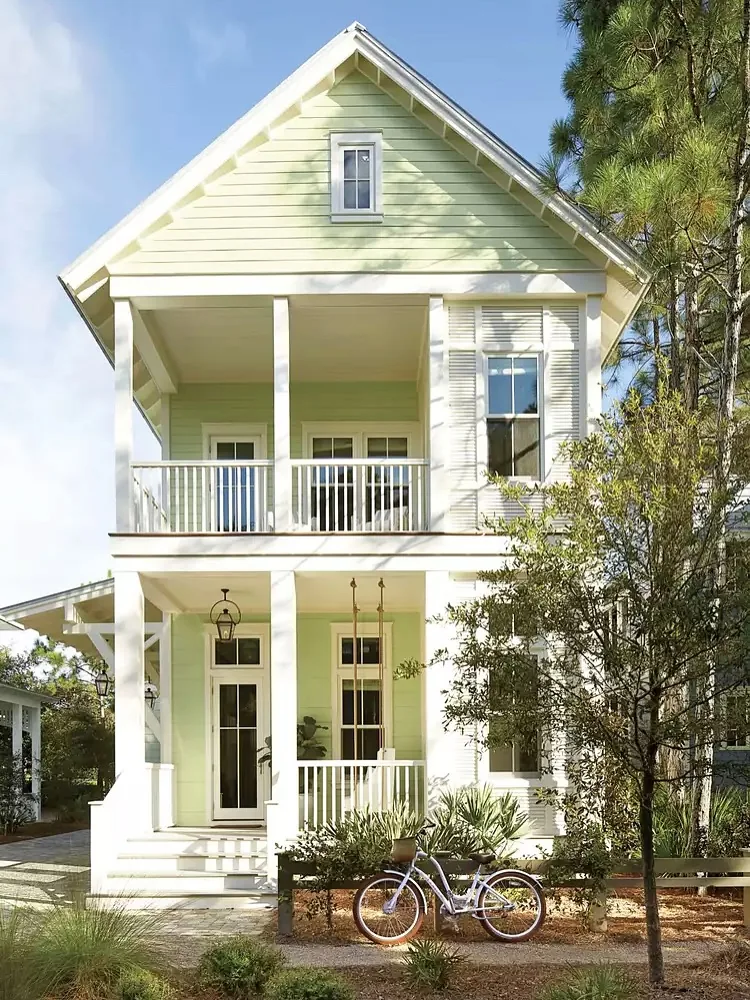 Pale green double porch cottage with a bike