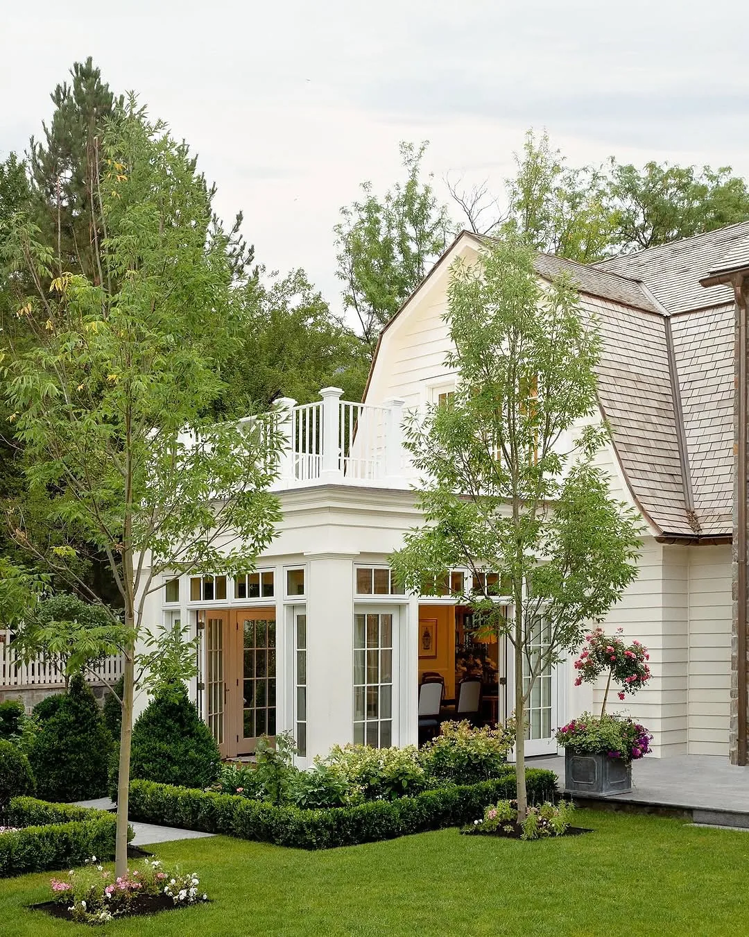 White cottage with a bay window and manicured garden