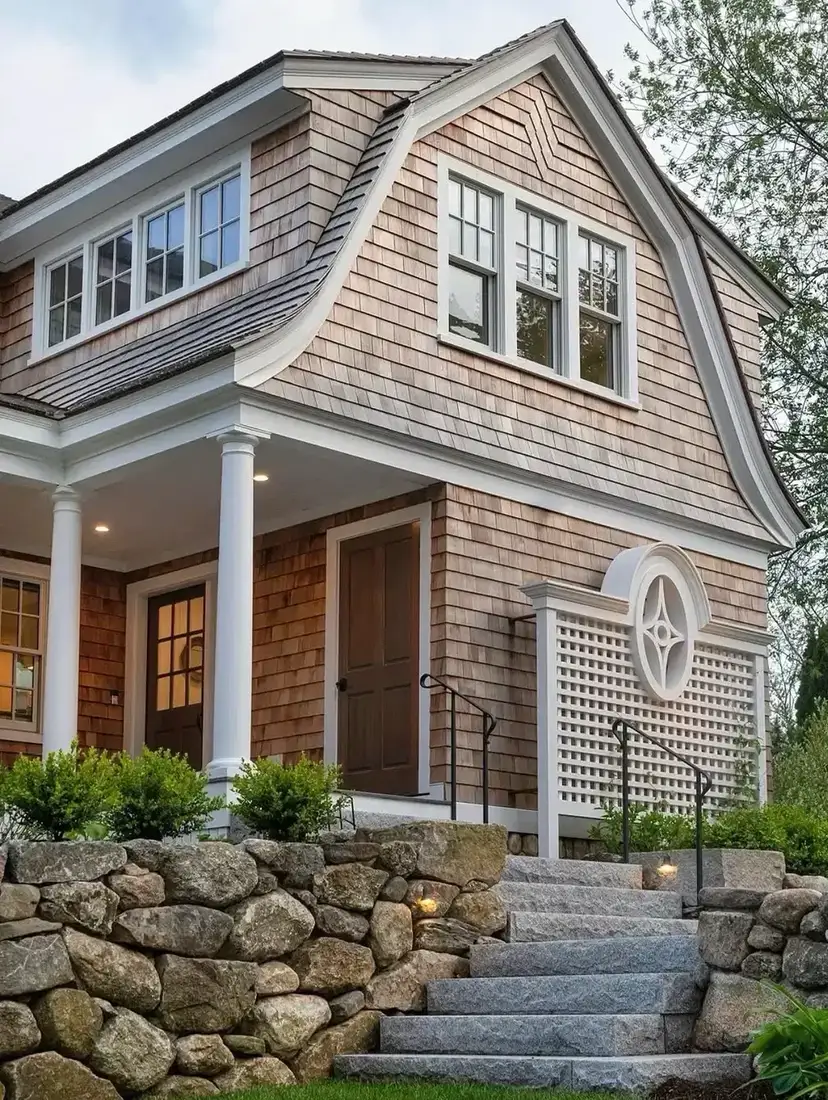 Gambrel shingle carriage house with fieldstone wall and gravel drive