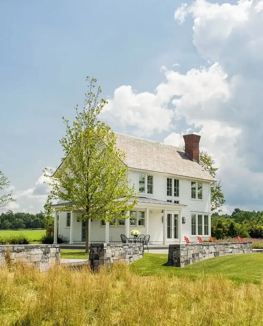 Classic white farmhouse exterior with board siding and open lawn