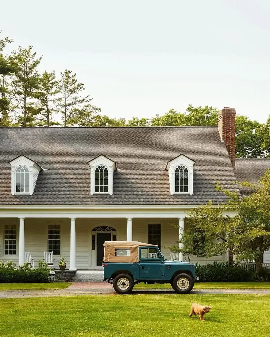 White Cape Cod farmhouse with dormer windows above a covered front porch