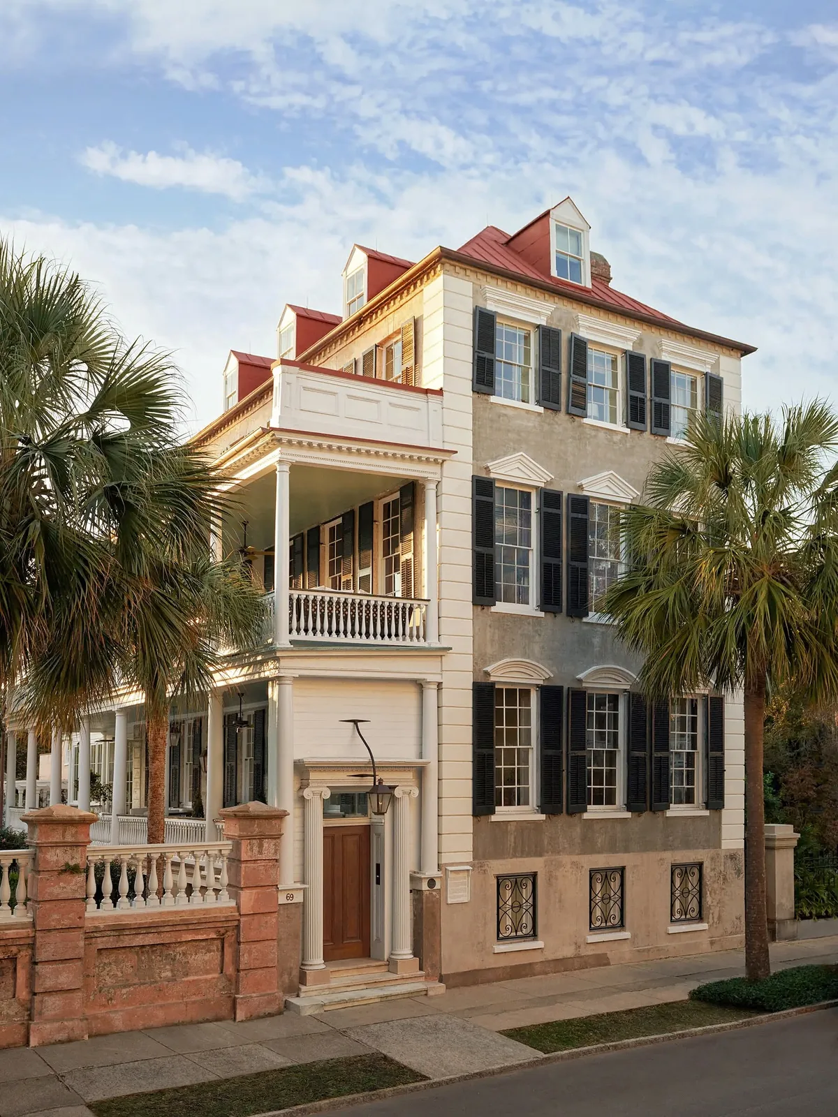 Charleston stucco townhouse with black shutters and palms