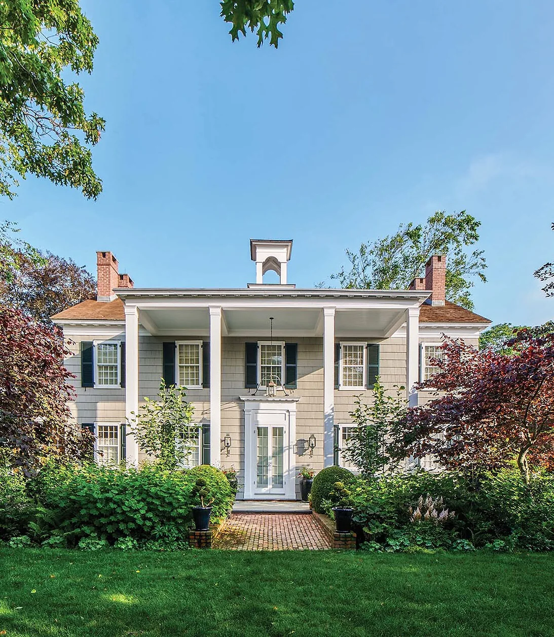 Cream Greek Revival house with a cupola and columns