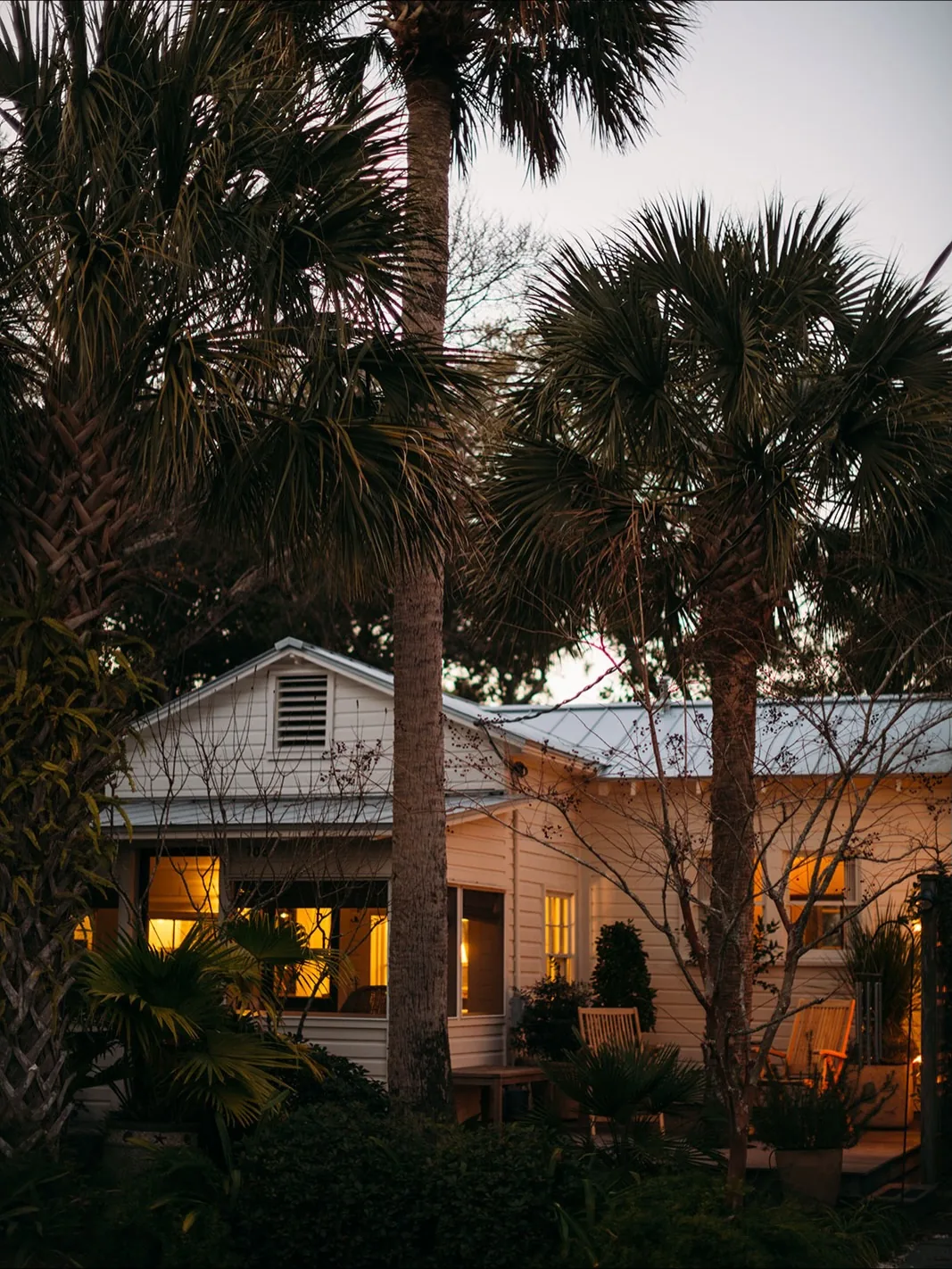 White cottage with palm trees glowing in the evening