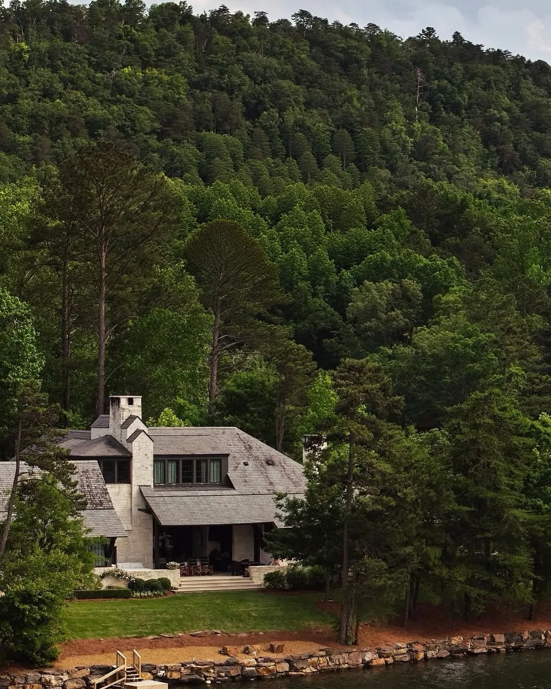 White lake house on a forested mountain hillside