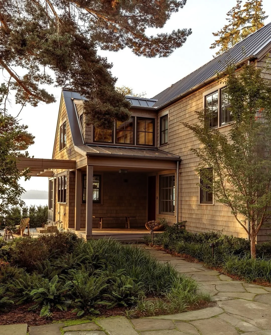 Cedar shingle coastal home with a dark metal roof