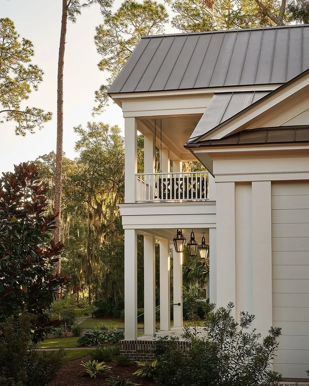 Cream stucco house with a metal roof and lantern lights by the door