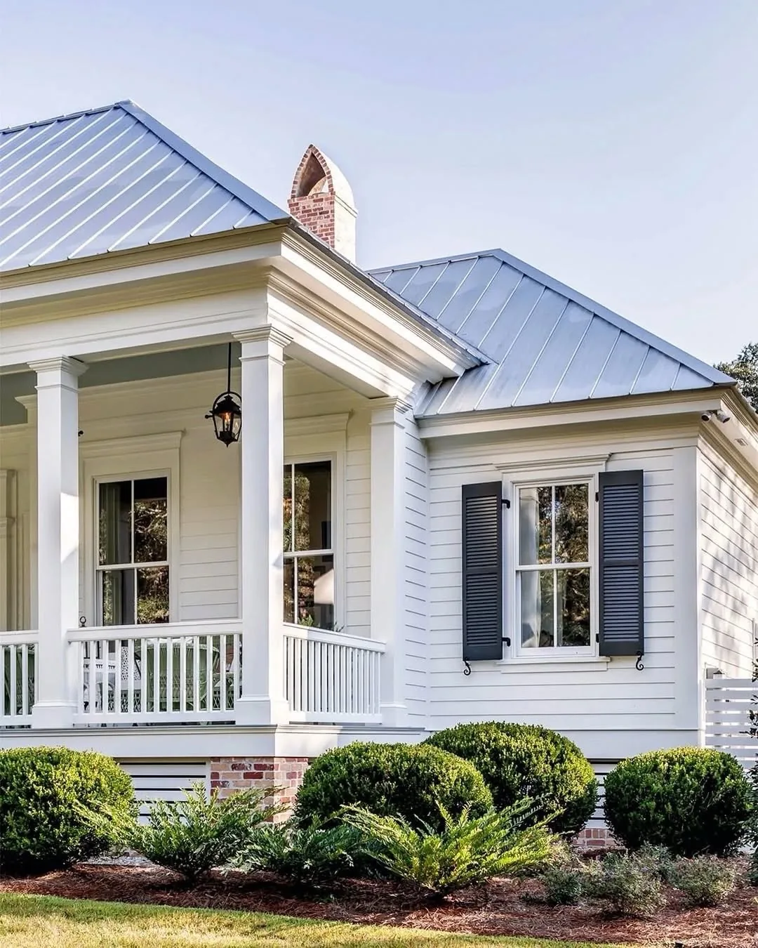 White clapboard house with a blue metal roof and porch columns