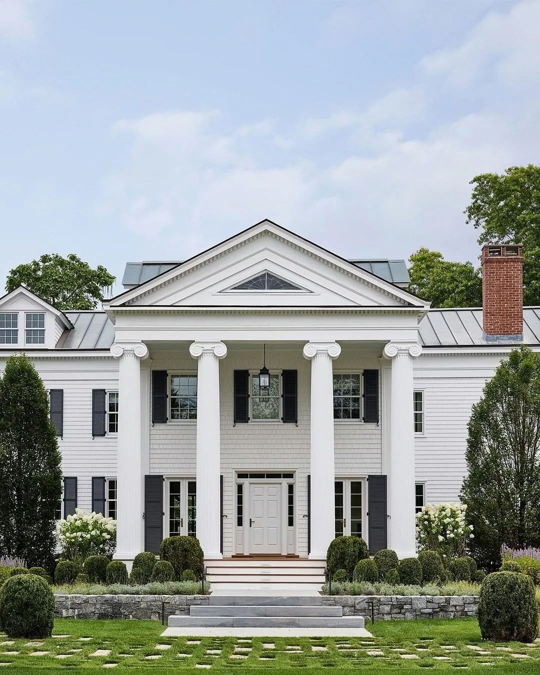 White Greek revival house with tall columns and a metal roof
