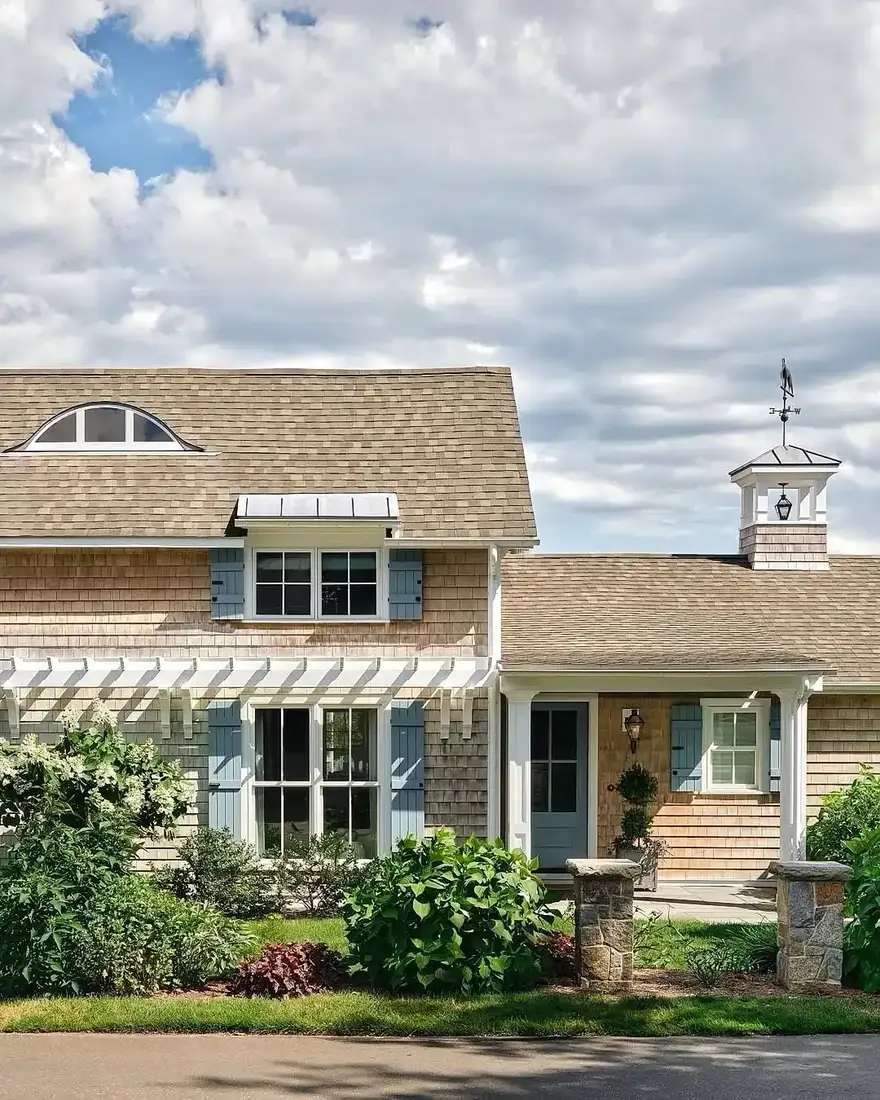 Shingle cottage with blue shutters and white cupola on the roof