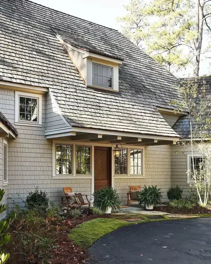 Shingle cottage with warm wood door and curved gravel driveway