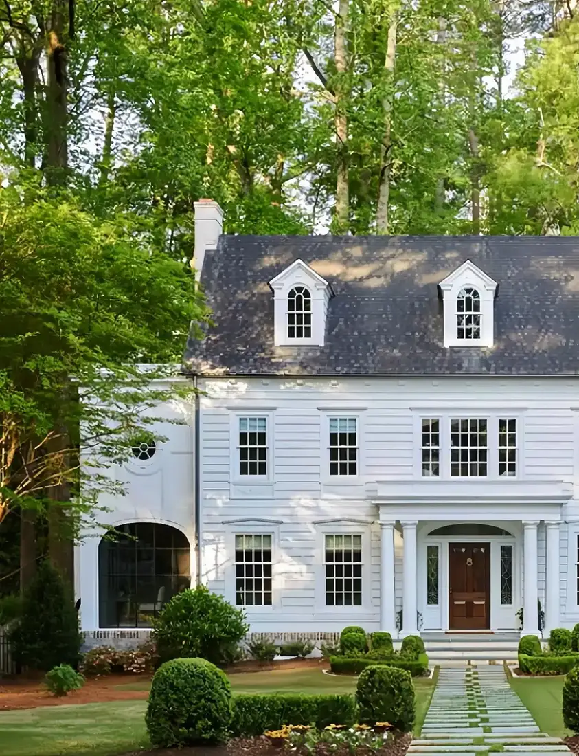 White clapboard colonial with boxwood balls and stone path to the front door