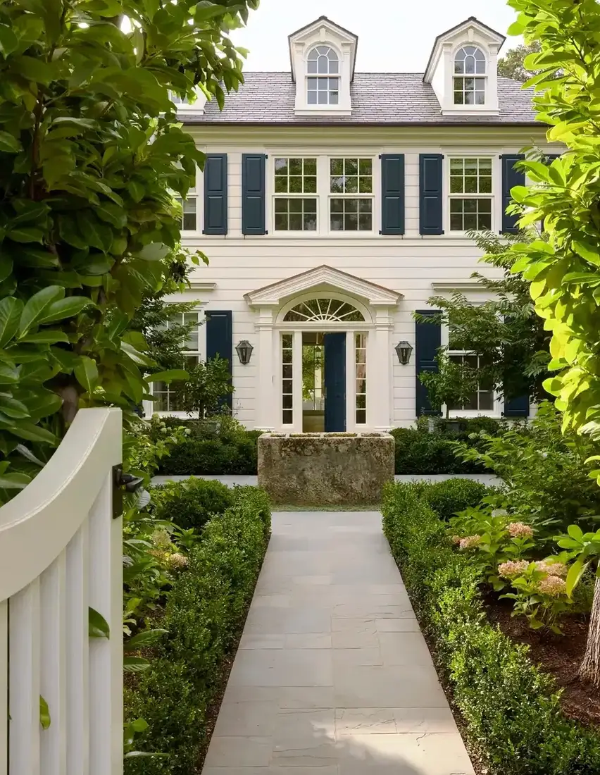 White colonial with black shutters and narrow stone path through the lawn