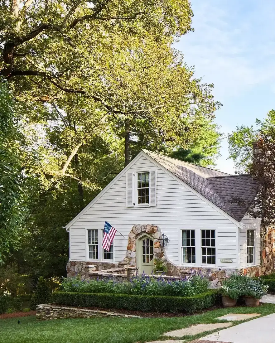 White cottage with stone arched entry and small flag by the door