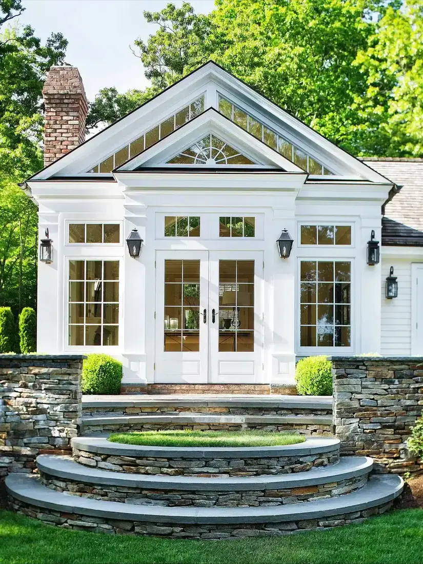 White house exterior with wide stone terrace and garden beyond
