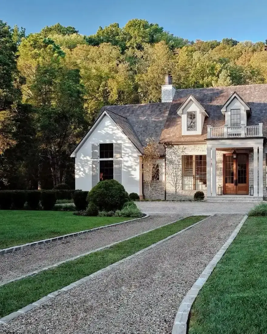White stone cottage with warm gravel driveway and clipped hedges