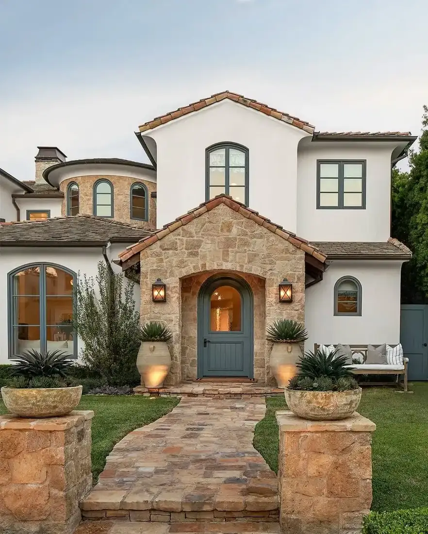 White stucco house with stone arched entry and flagstone path