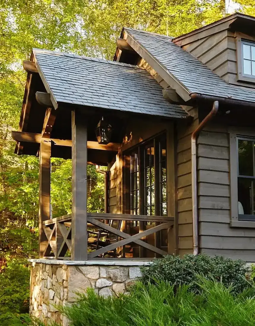 Rustic cedar cabin with stone foundation and covered front porch
