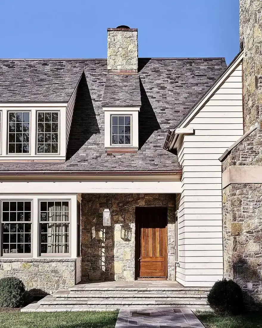 Stone and clapboard cottage with slate roof and tall chimney