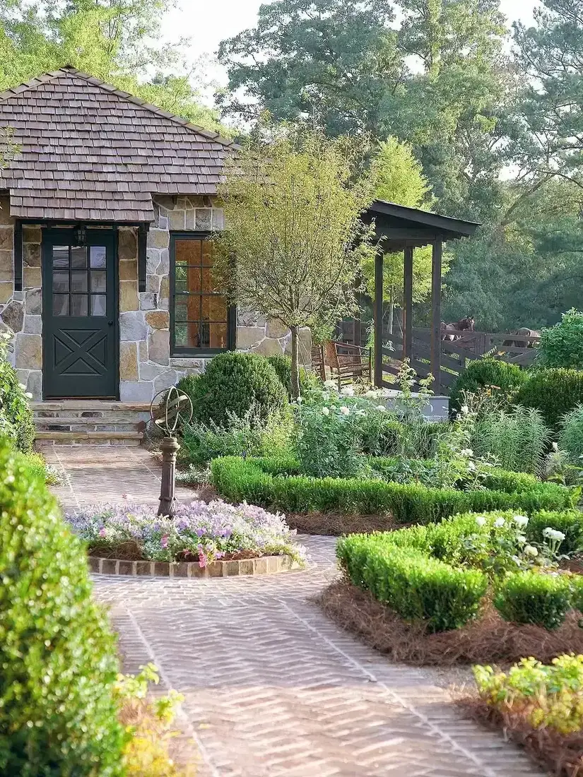 Stone cottage with black front door and boxwood parterre garden