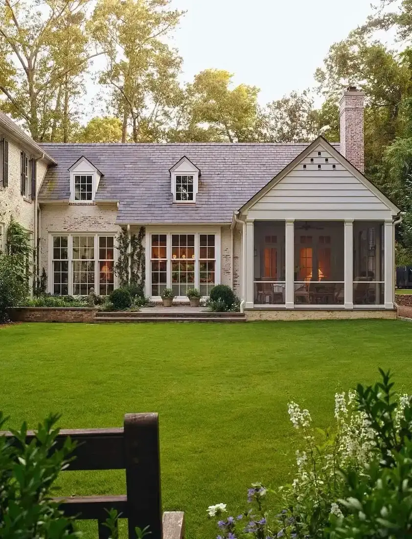 Stone cottage with screened porch and green lawn in front